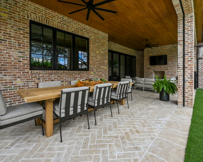 Outdoor patio with wooden table, chairs against a brick wall, and sand limestone flooring.
