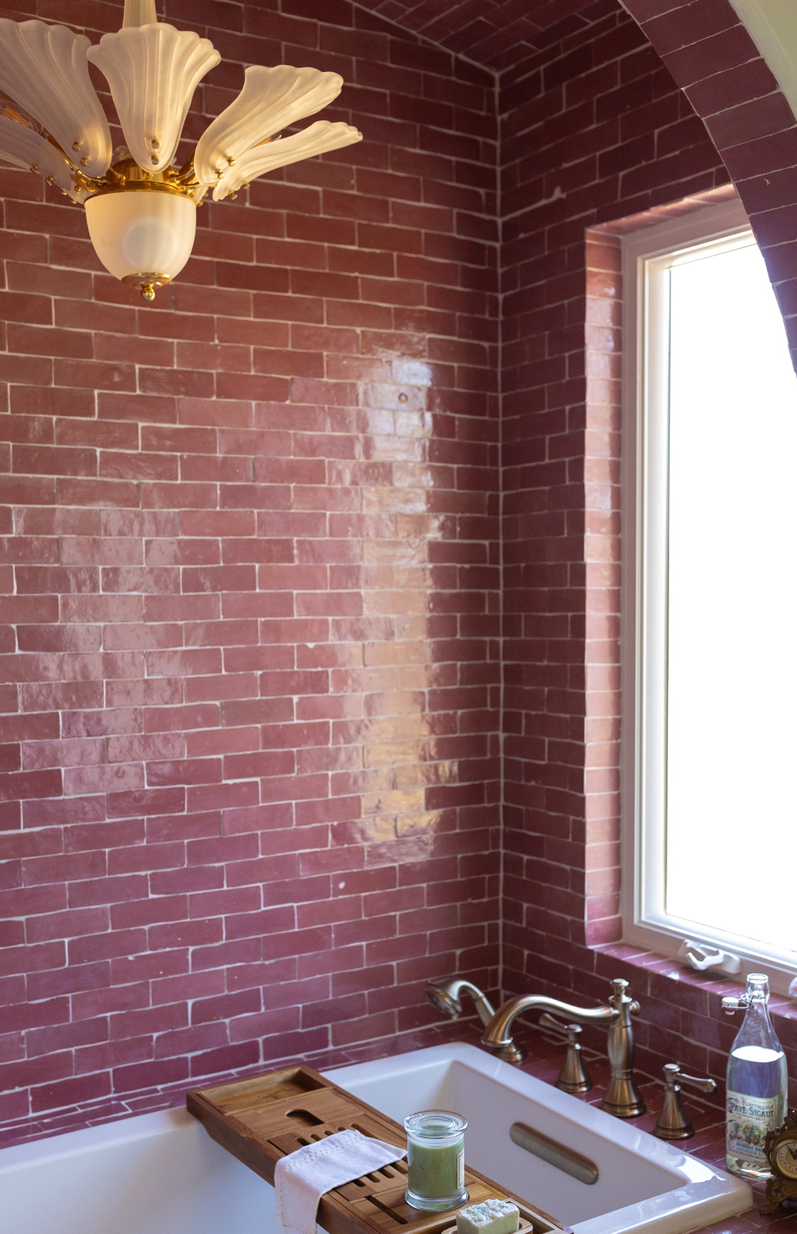 Bathroom with red brick walls, a bathtub, and a window.