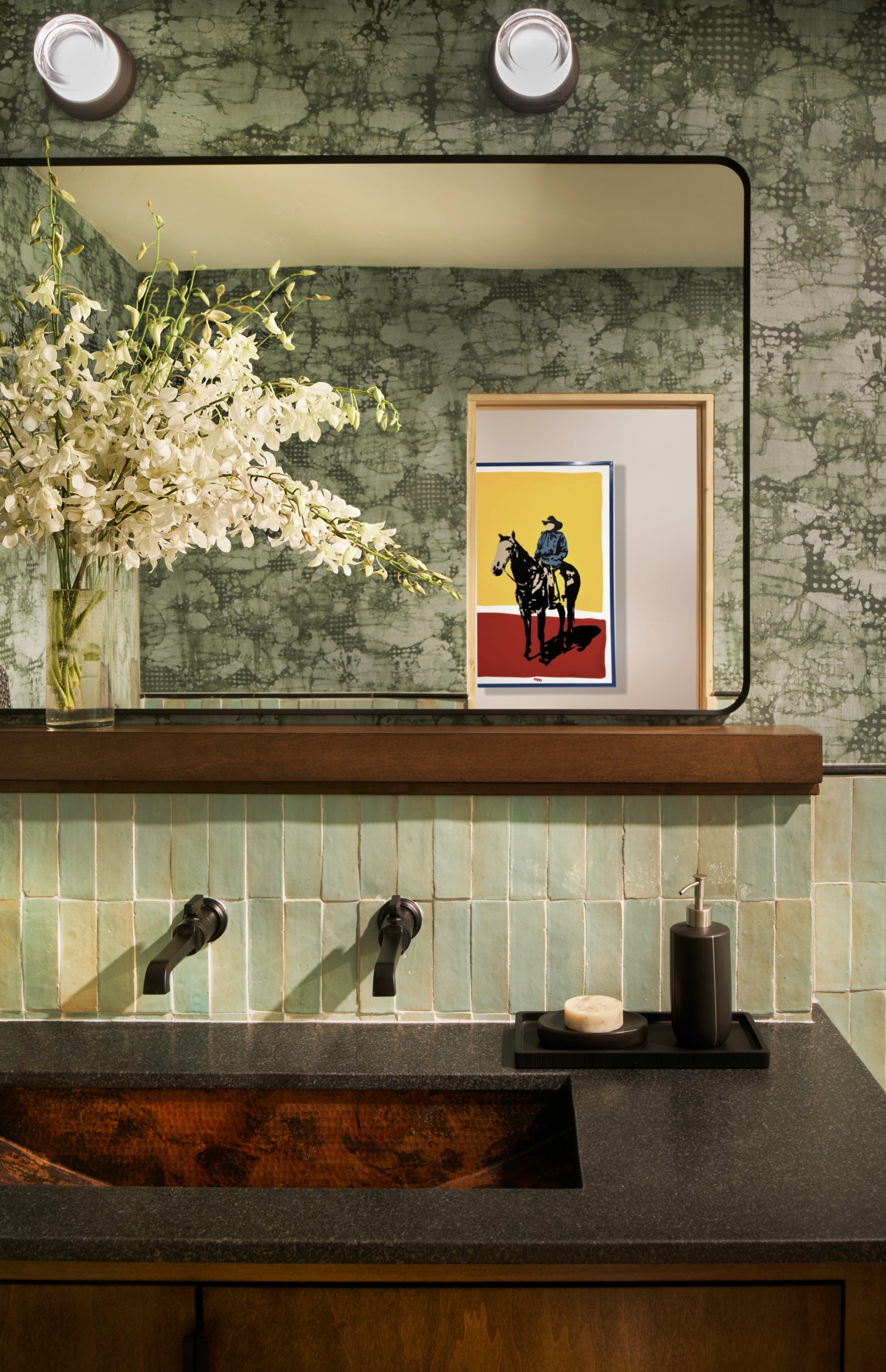 Bathroom interior with green tiled wall, mirror, and decorative elements.