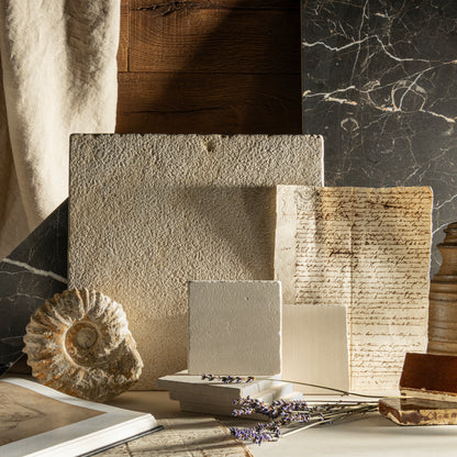 Collection of textured limestone and books on a marble surface with a natural light setting.
