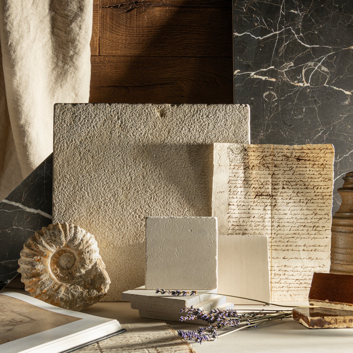 Collection of textured limestone and books on a marble surface with a natural light setting.