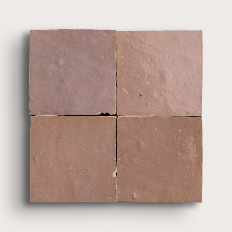 Four zellige square tiles with a brownish-red color on a white background