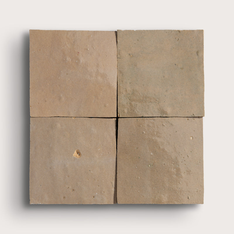 Brown square zellige tile with a small chip on a white background