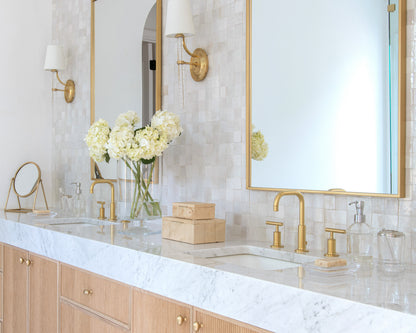 Bathroom vanity with marble countertop, gold fixtures, and zellige backsplash tile.